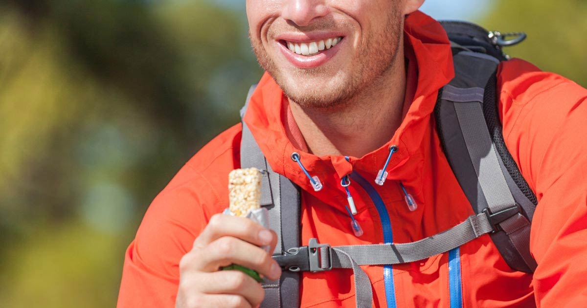 Male hiker taking a break and eating a granola bar